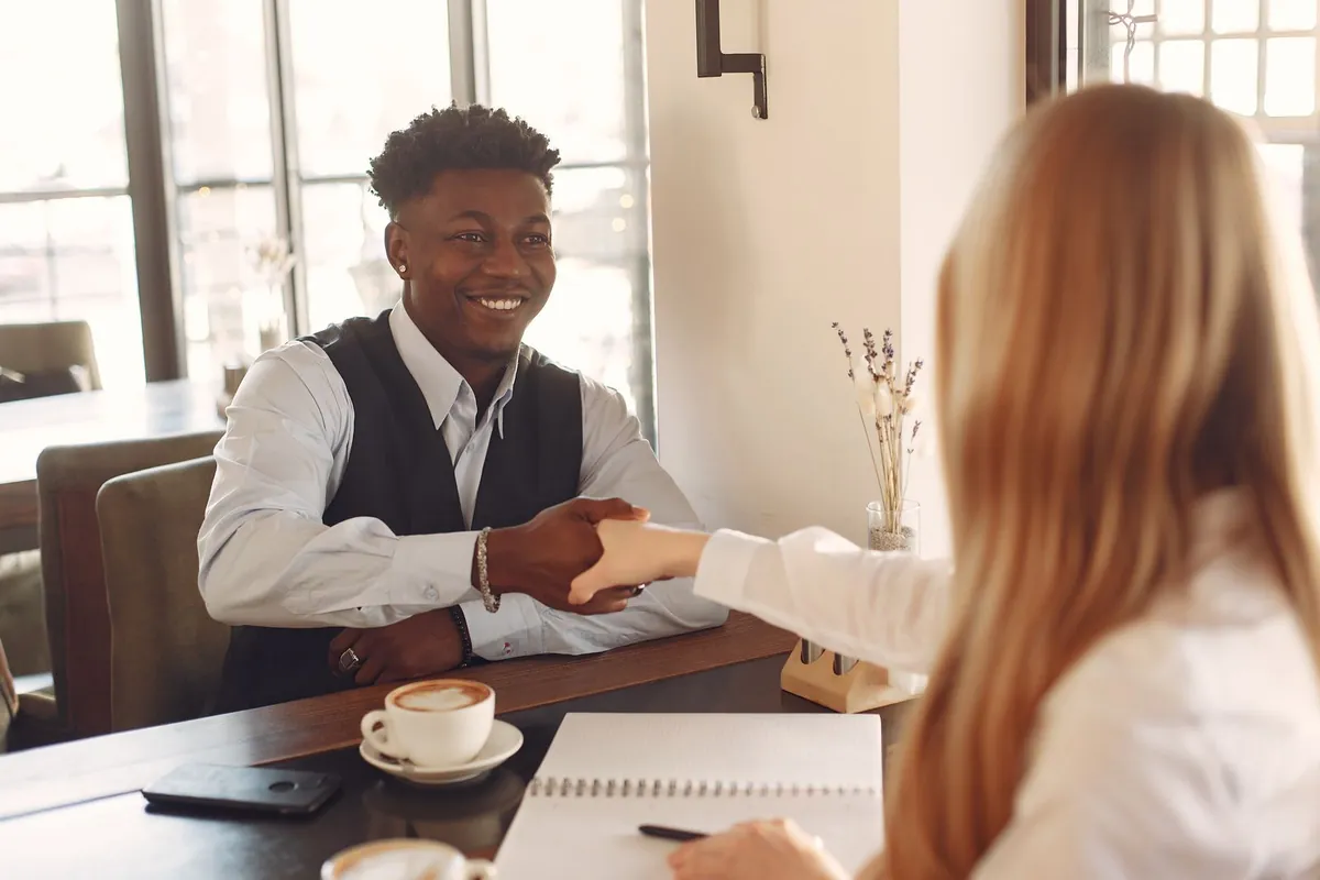 Two people shaking hands across a café table